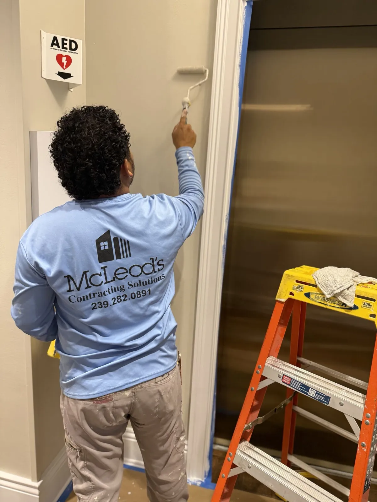 McLeod's Construction painter repainting a hallway wall at Pelican Isles Yacht Club