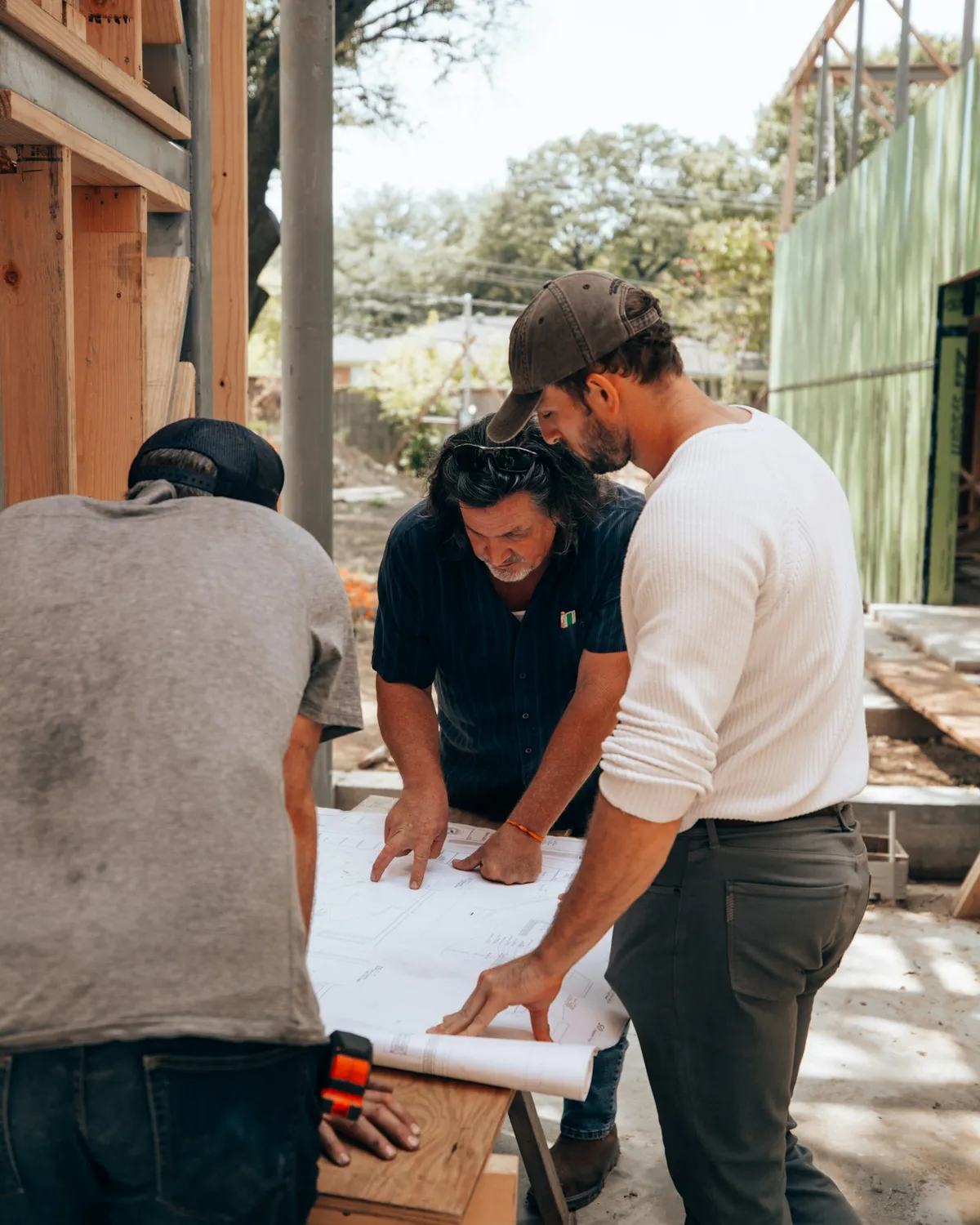Contractor team reviewing building plans together at a construction site during a pre-construction meeting