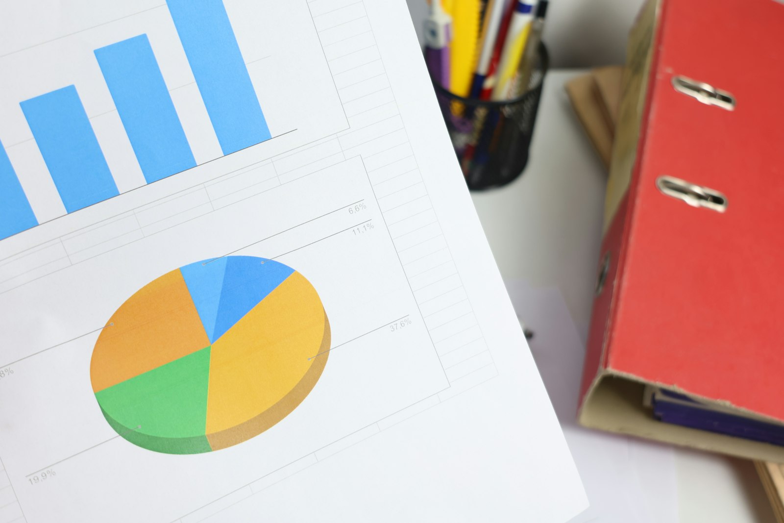 Financial report with bar and pie charts next to a binder and pens, representing a condo reserve study budget review