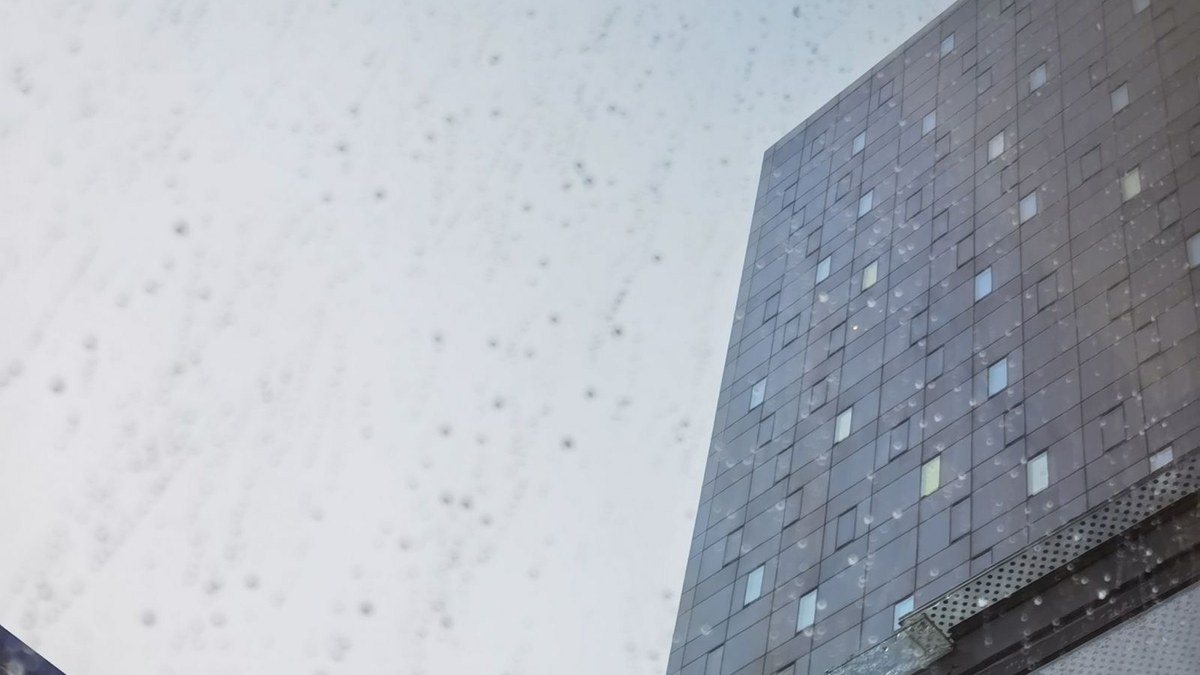 Rain running down glass with a high-rise building facade above during a Southwest Florida storm