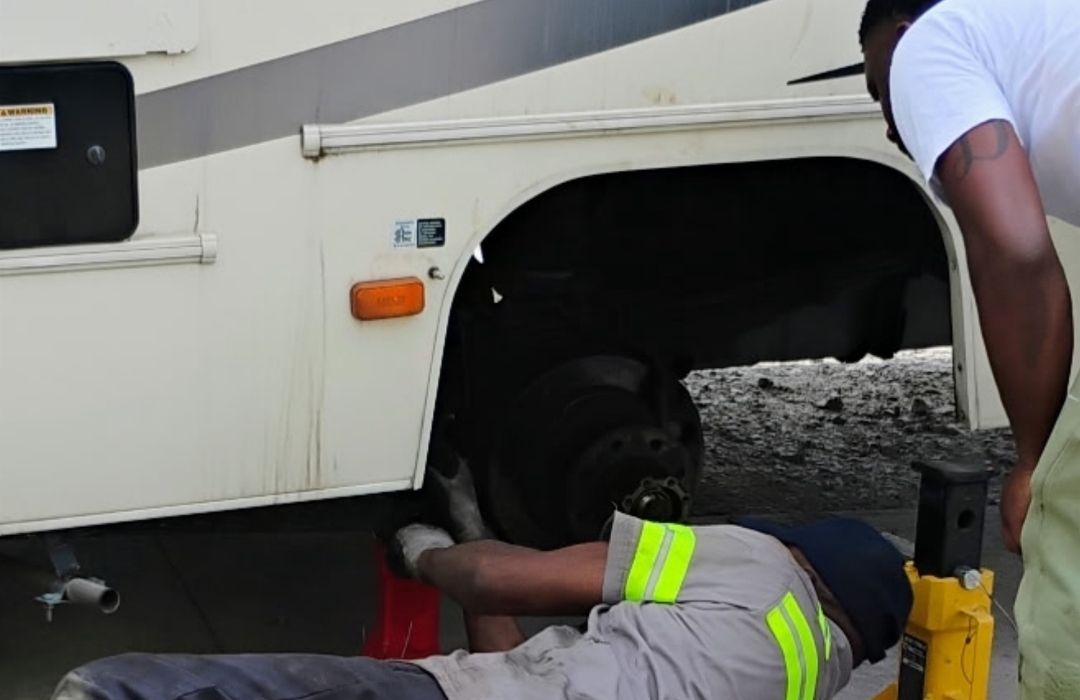 Technician servicing the wheel and chassis of a motorhome