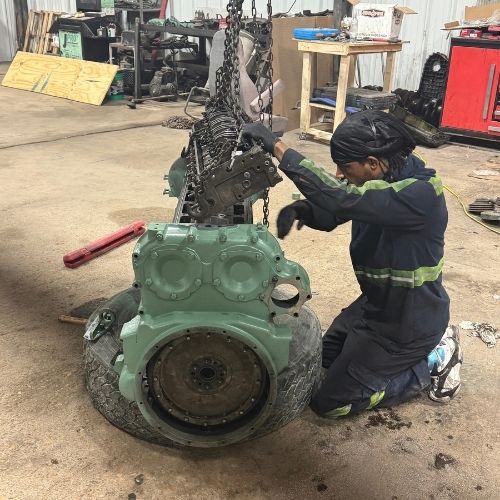 Technician working on a removed green diesel engine on the shop floor