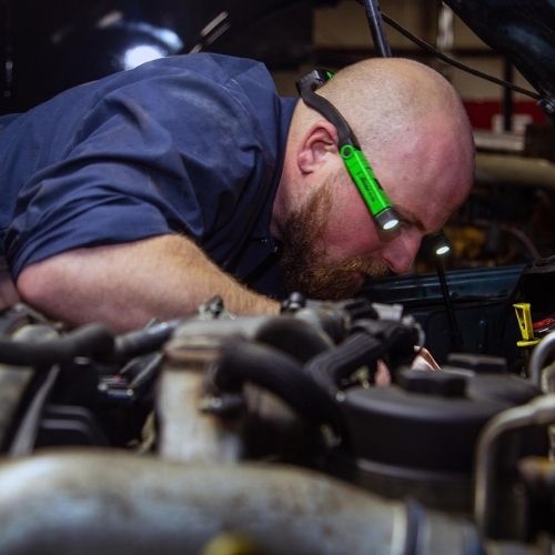 Mechanic closely inspecting engine components during diagnostics