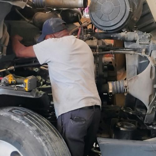 Mechanic working inside a heavy truck engine compartment