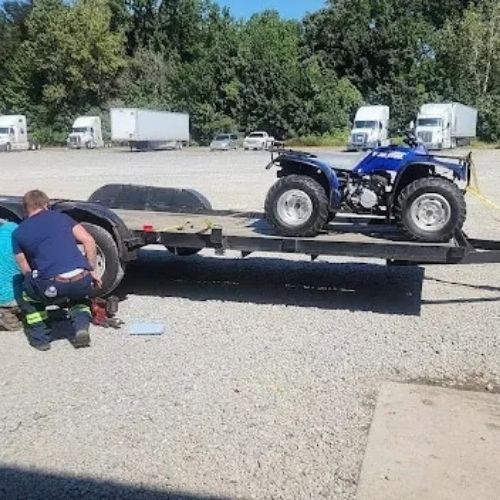 Mechanic repairing a flatbed trailer in a truck stop parking lot