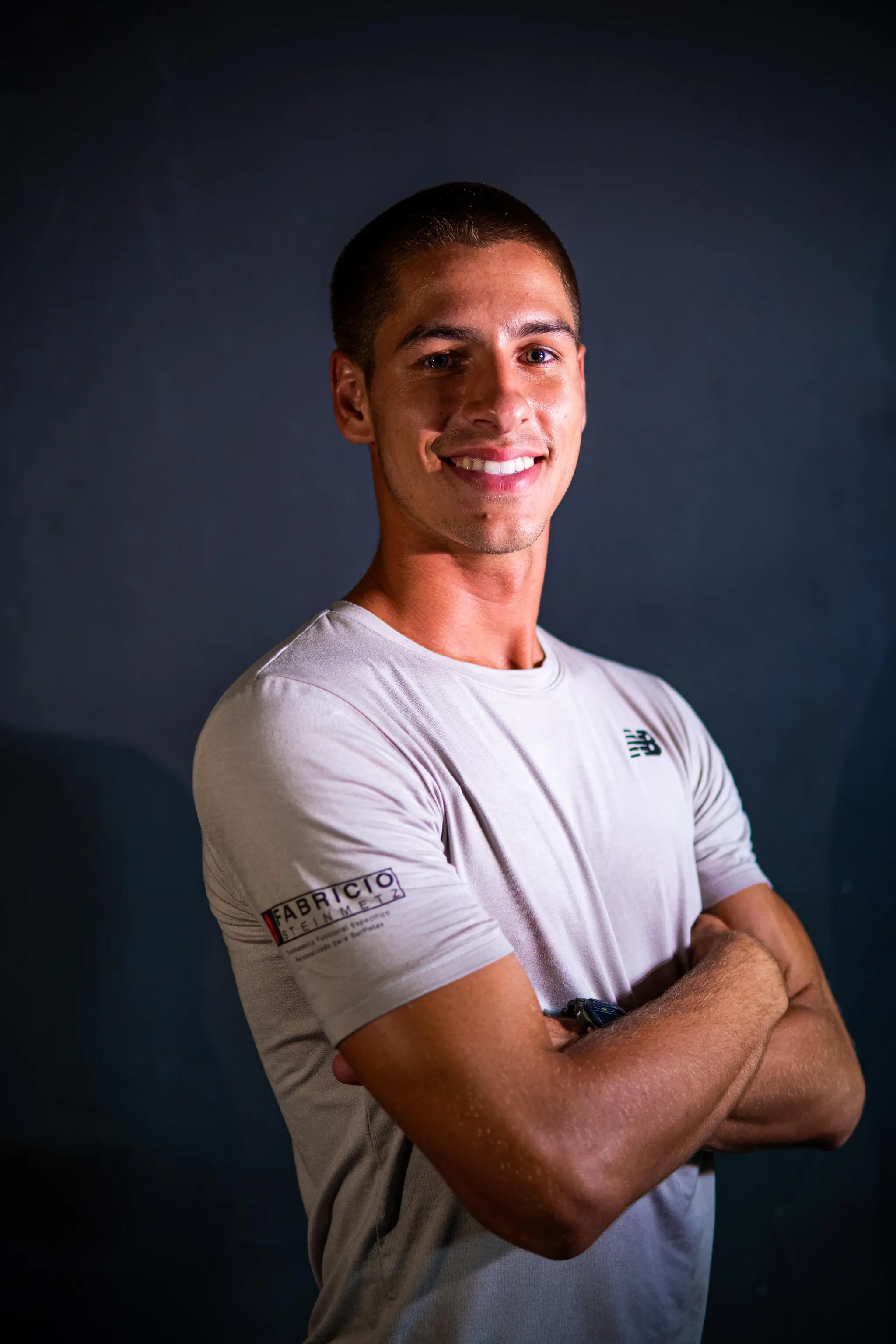 Surfcoach Fabrício Steinmetz em pé com prancha na beira da praia