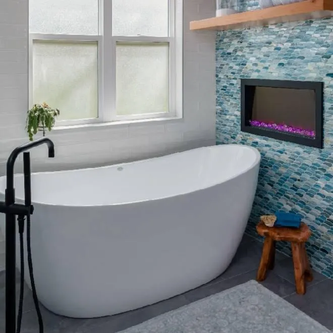 Freestanding bathtub with blue accent wall and electric fireplace