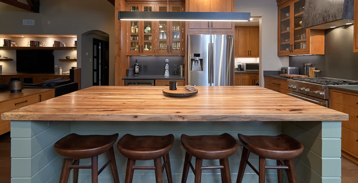 Modern living room with a stone fireplace, light hardwood floors, and vaulted ceilings.