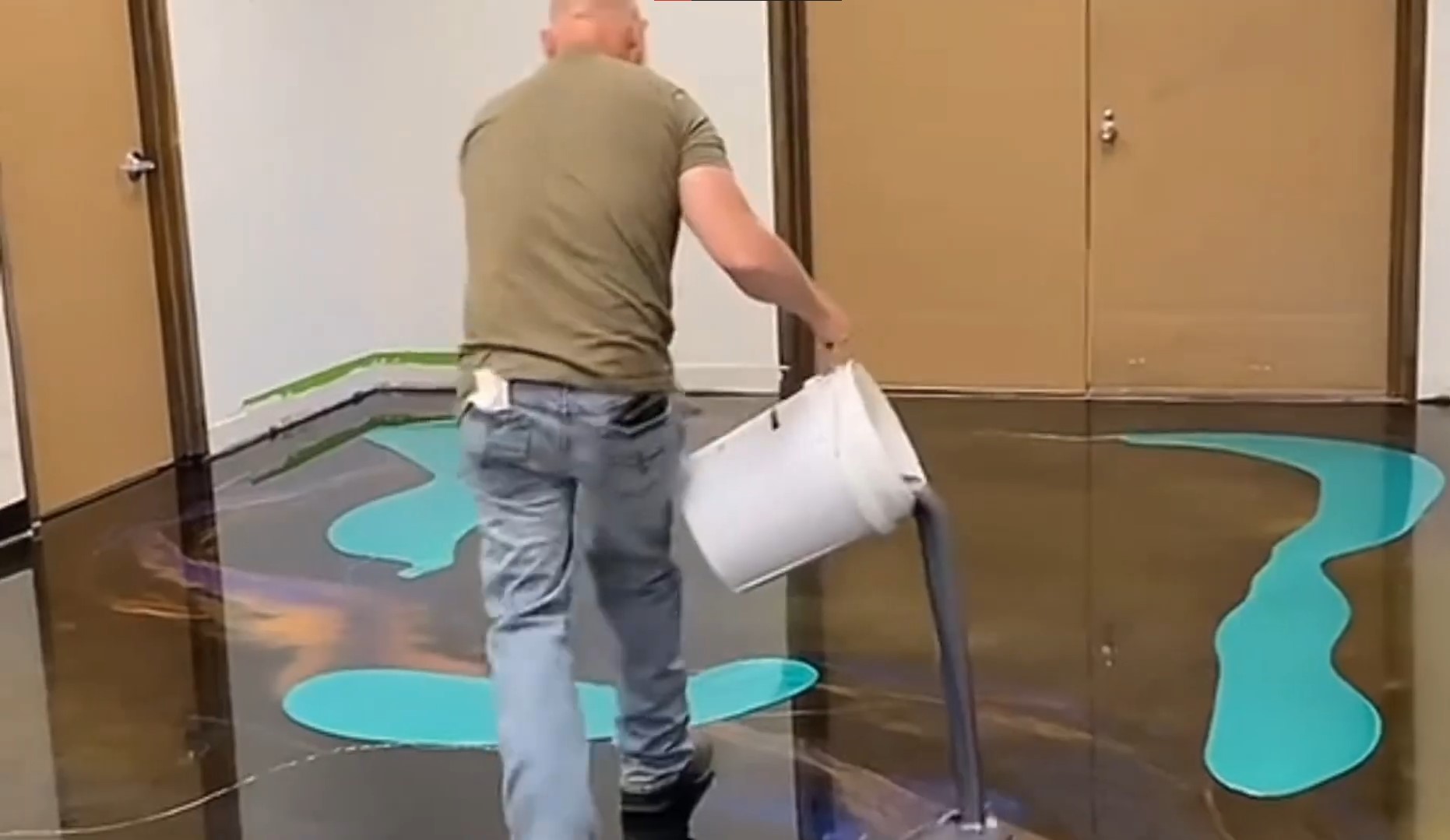 man pouring purple epoxy over metallic resin floor with white bucket