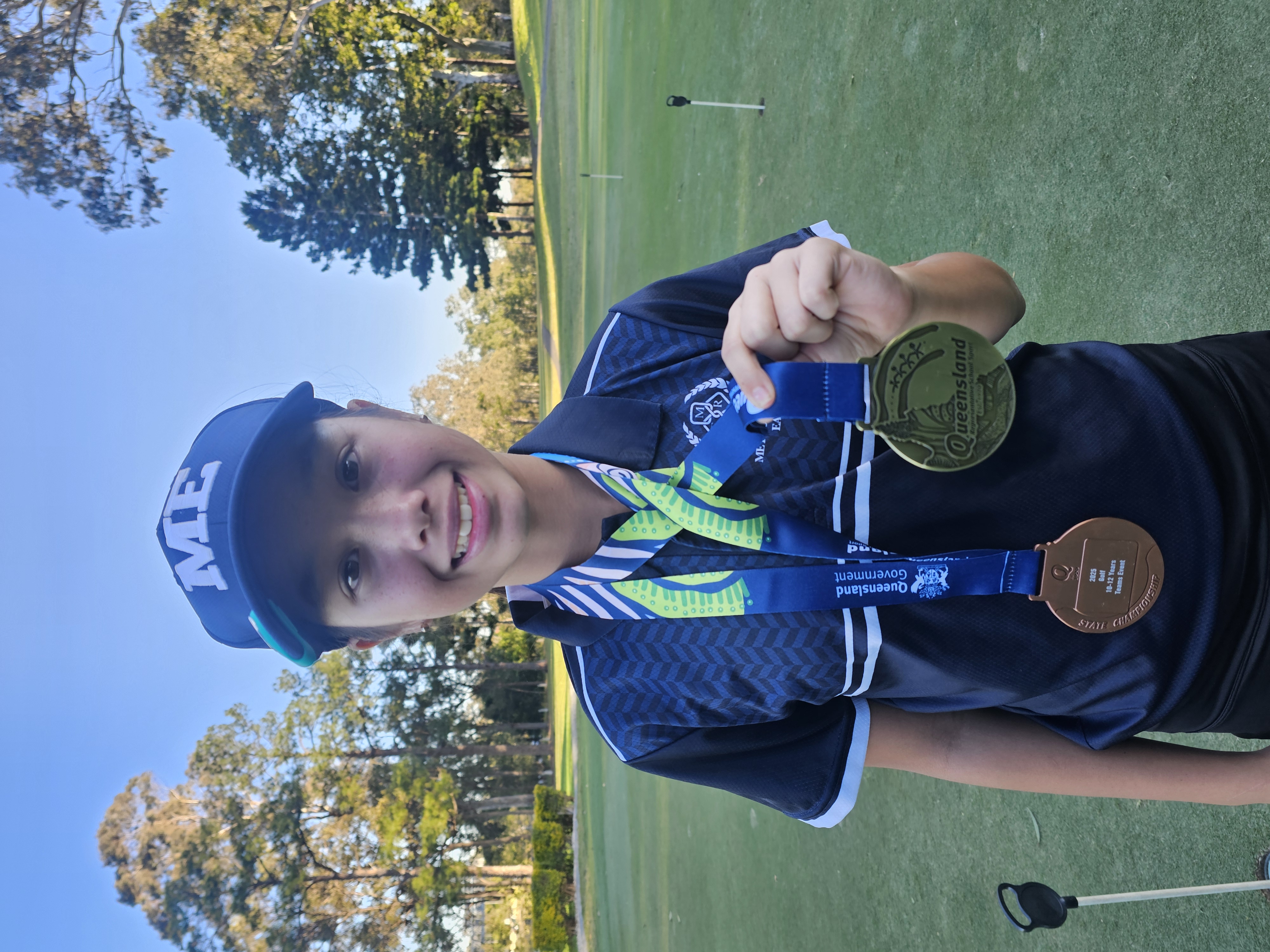 Three-quarter portrait of junior golfer Chloe Tennent in Meadowbrook golf polo, smiling and holding a putter.