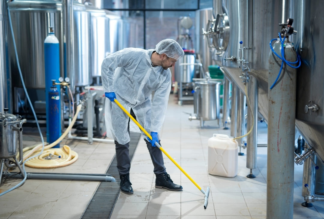 industrial worker using a commerical cleaning tool to clean the floor of a factory