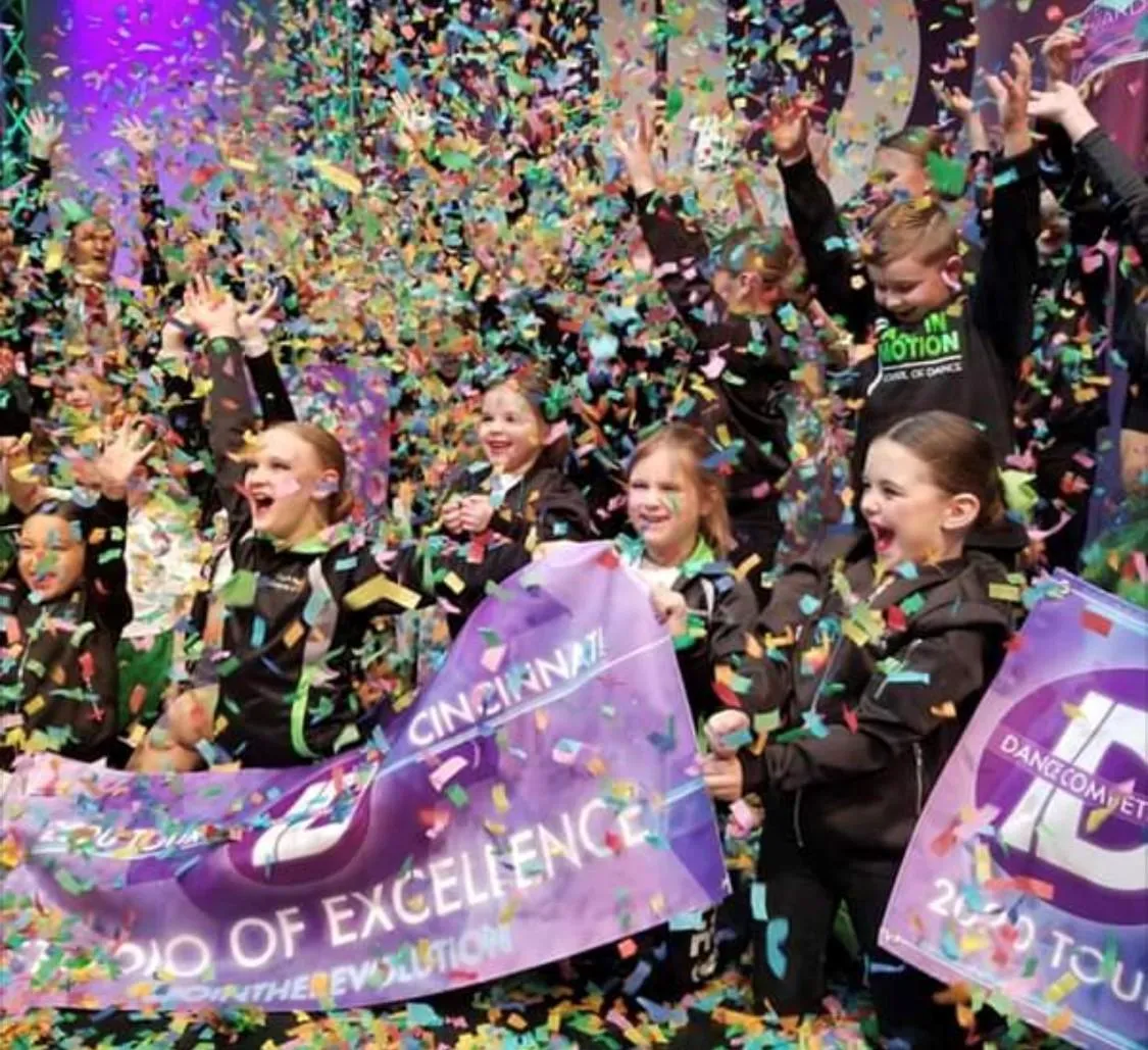 Dancers celebrating on stage with colorful confetti falling around them.