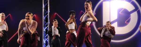 Dancers in Maroon and White costume with a shocked facial expression while on stage