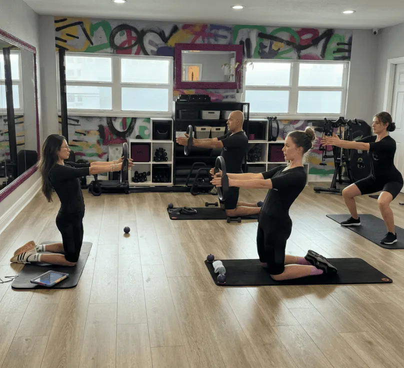 Coach guiding a small group through EMS-assisted exercises in a bright modern studio