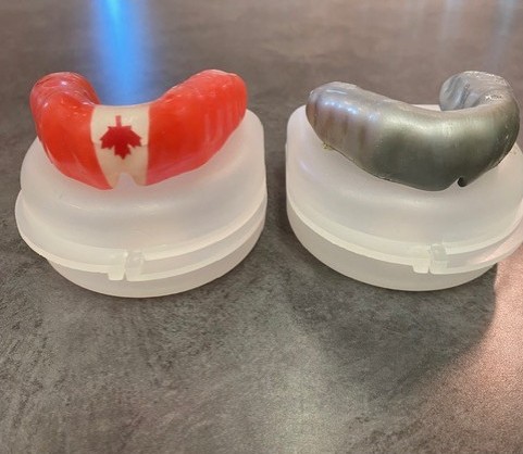 Two different custom made mouthguards; left one in canadian flag color, right one in grey color.
