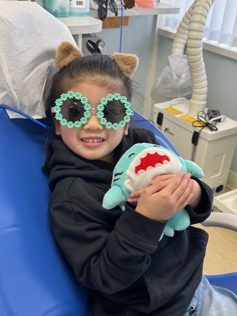 A young girl looking to get her teeth checked up by a dental assistant and hygienist 