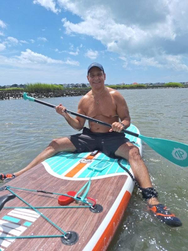man sitting on a paddleboard in the water smiling
