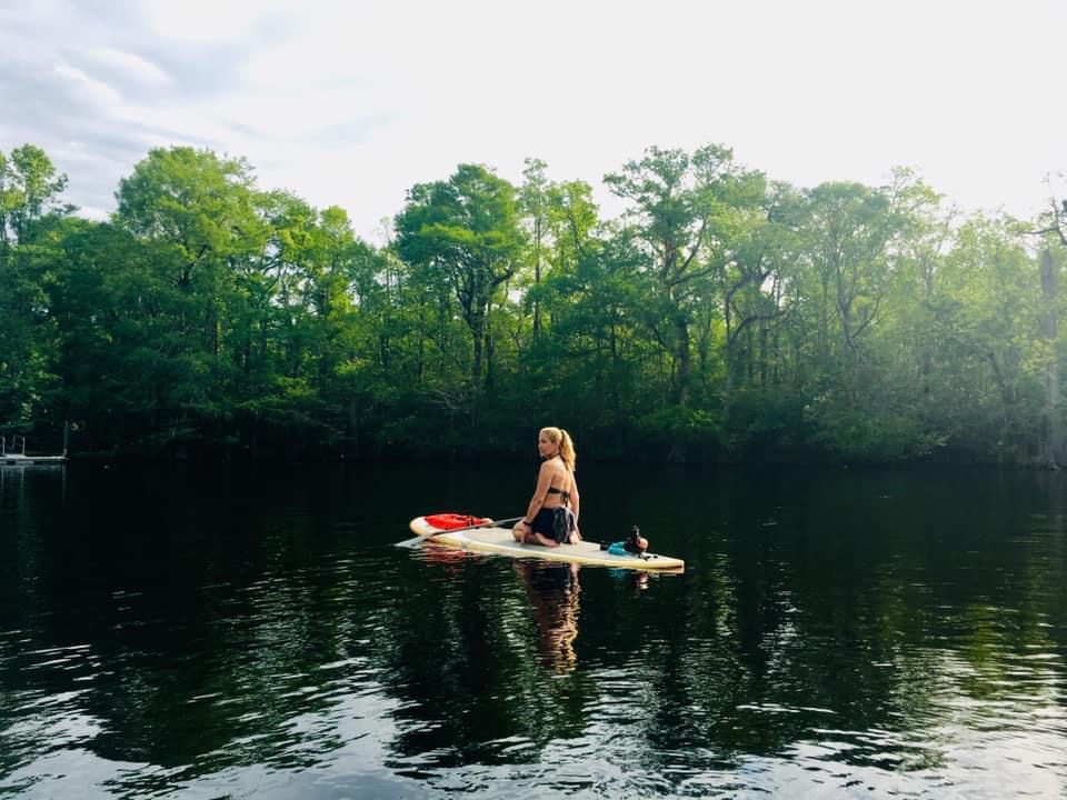 woman on a paddleboard on the river with trees around