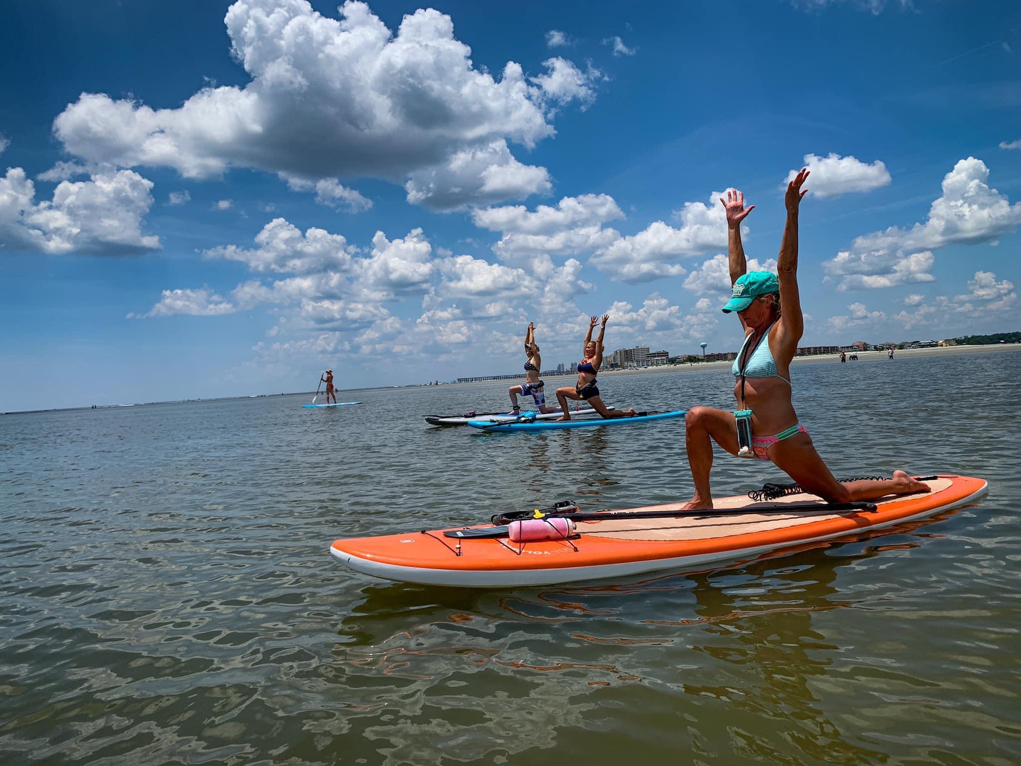 people on paddleboard doing yoga on the water