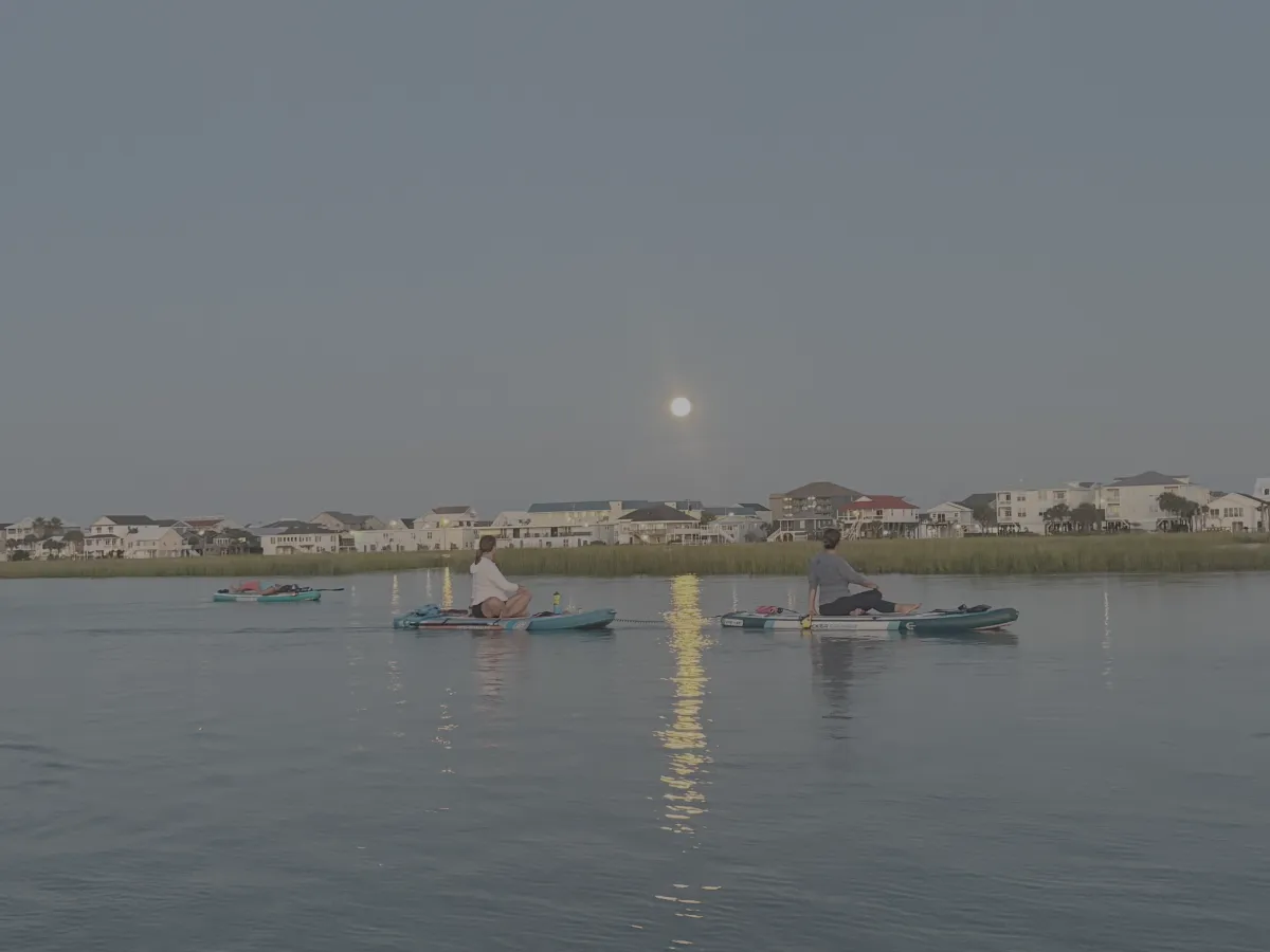 people on paddleboards doing yoga during full moon