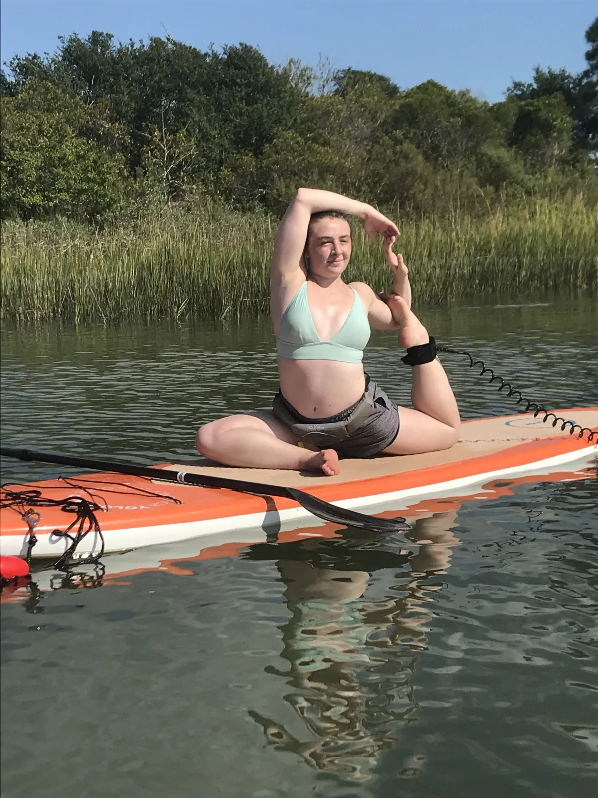 woman doing a yoga pose on a paddleboard