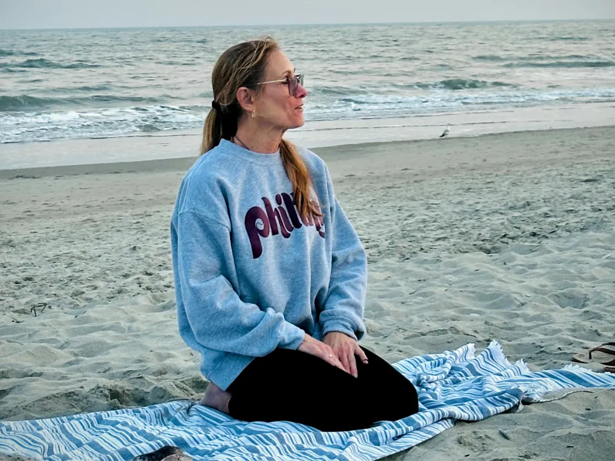 a woman kneeling on the beach 