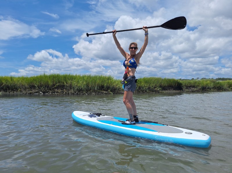 woman on a paddleboard holding her paddle in the air