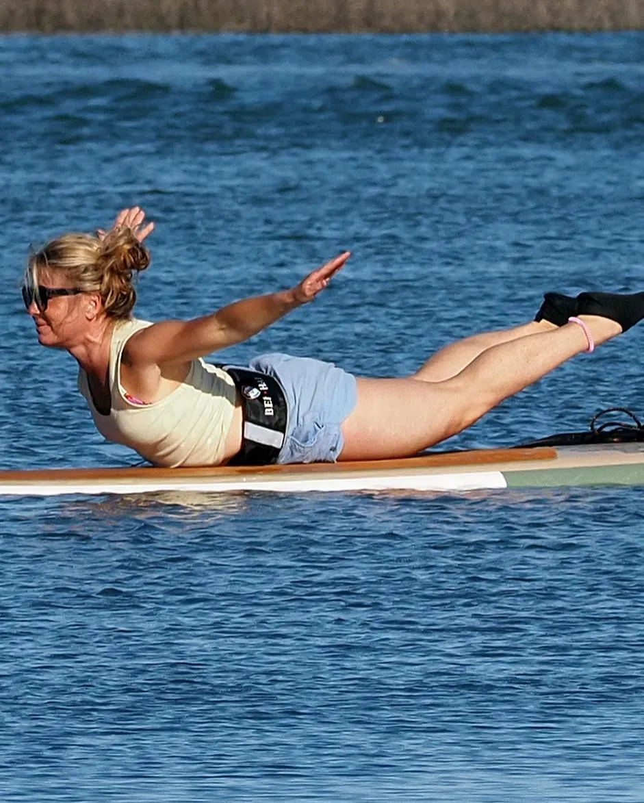 woman doing a yoga pose on a paddleboard