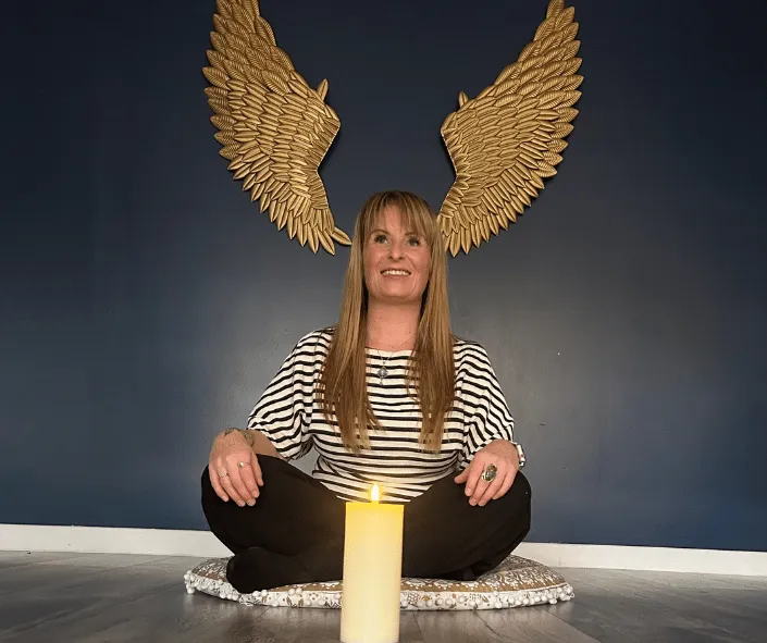 image of founder of saturn therapies siting in a meditation style with a candle