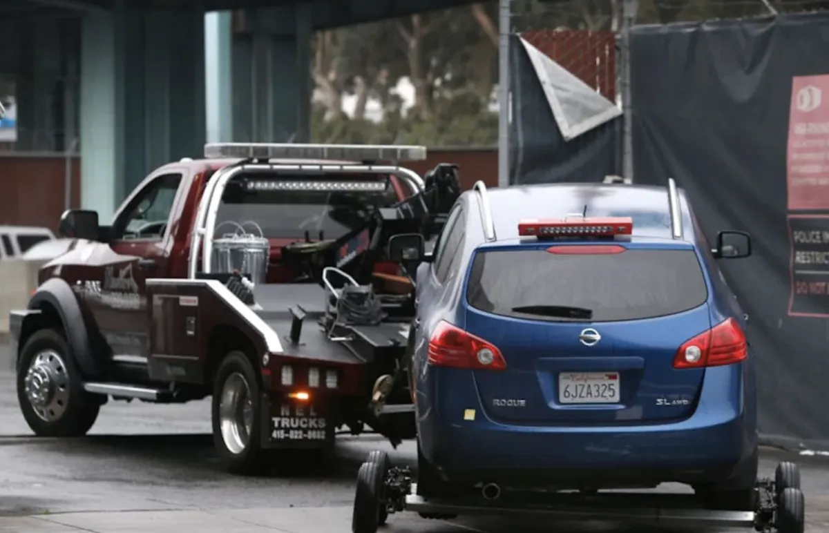 Tow truck towing a blue Nissan Rogue in California, illustrating vehicle removal during enforcement action related to insurance compliance and regulatory oversight.