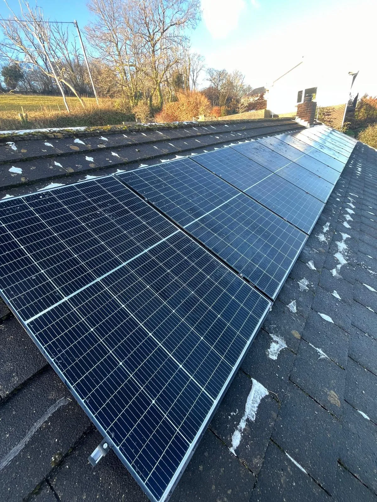 Solar panels fitted on a roof with a little bit of snow left on it