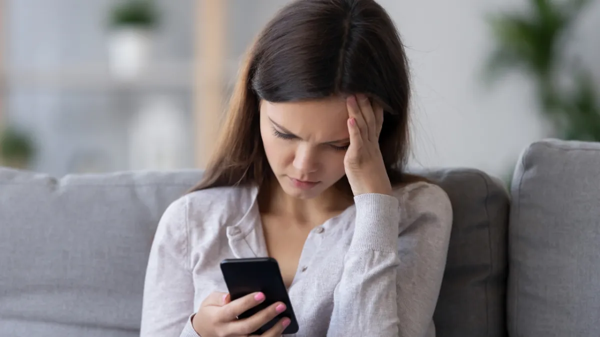 Woman staring at her phone, looking stressed