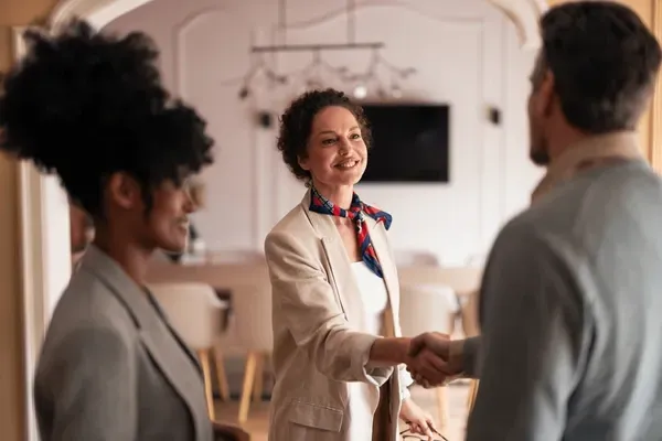 A woman smiling and shaking a man's hand