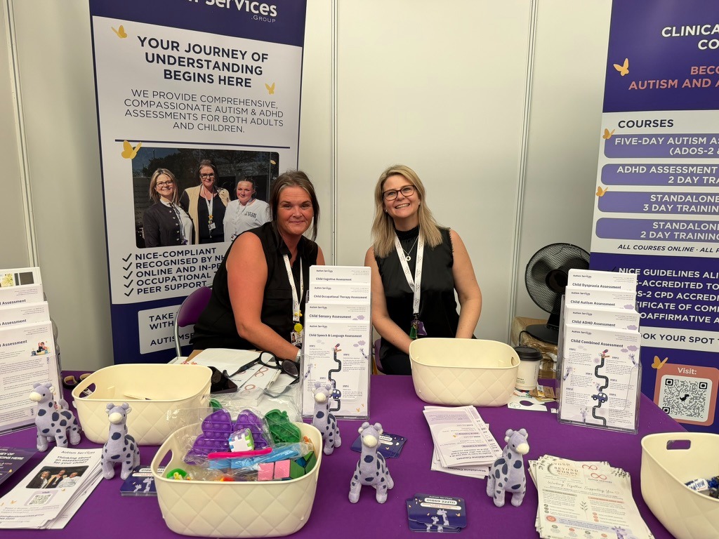 Team representatives from Autism Services Group at an information booth discussing neurodivergent support services.