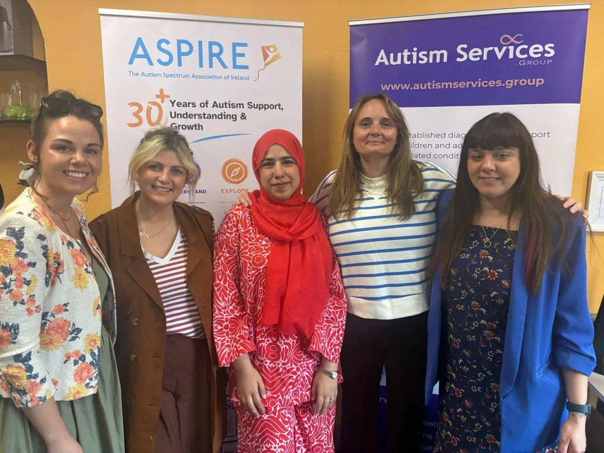 Team members from Autism Services Group and Aspire standing together in front of organizational banners.