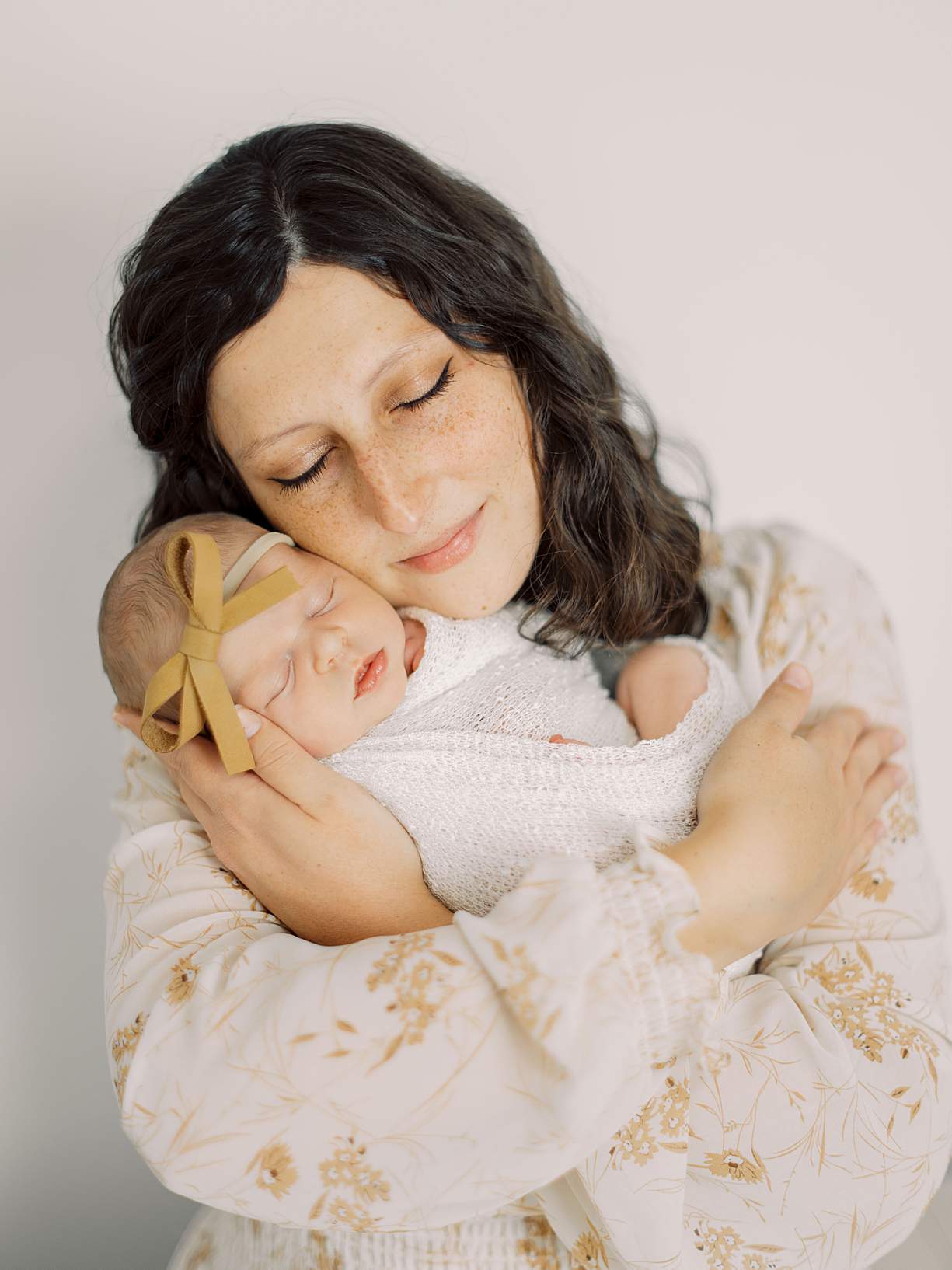 Newborn baby wrapped in neutral tones during lifestyle photography session