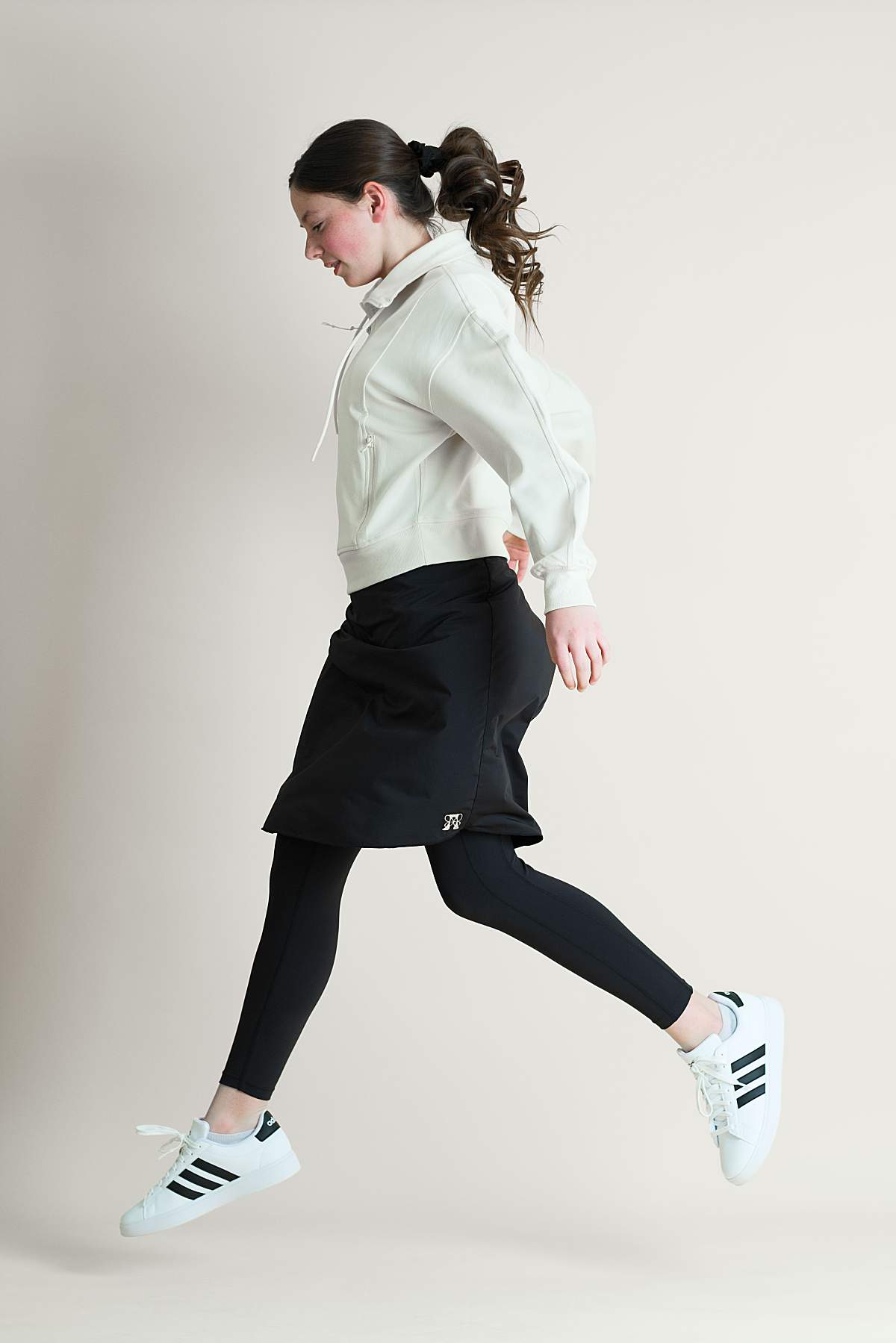 Teen girl jumping in the air while wearing a modest athletic skirt
