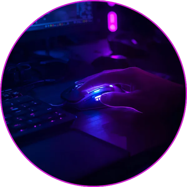 A person’s hand using a glowing RGB gaming mouse next to a keyboard in a dim, neon-lit computer setup.