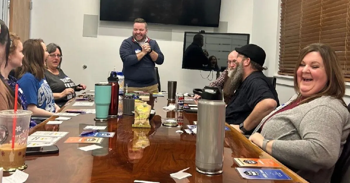 An interactive leadership training workshop in West Kentucky with Nathan Carter facilitating an engaged, laughing professional team around a boardroom table.