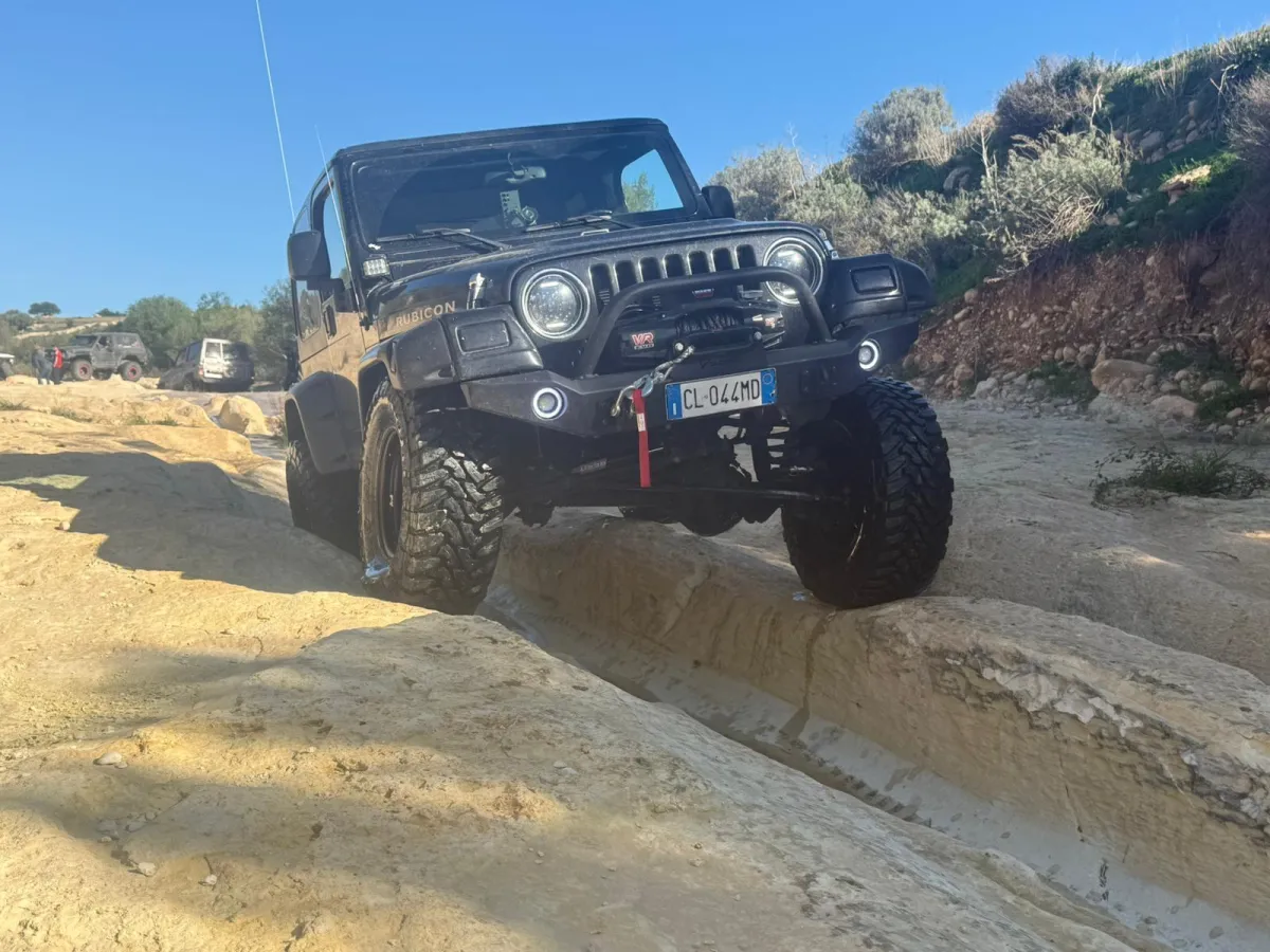 Yellow jeep driving on a muddy off-road trail