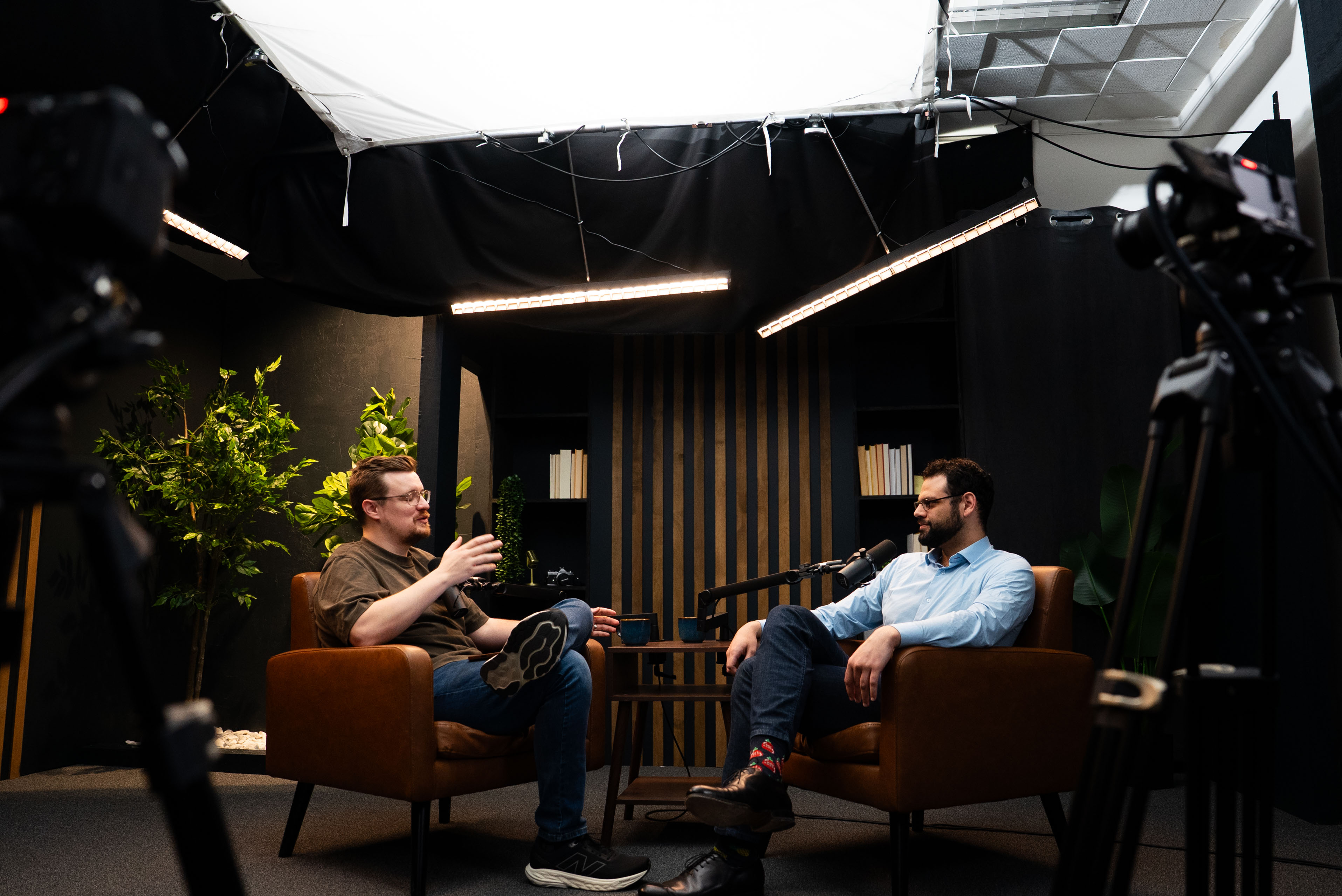 Two guys sitting in a comfy dark room recording a podcast
