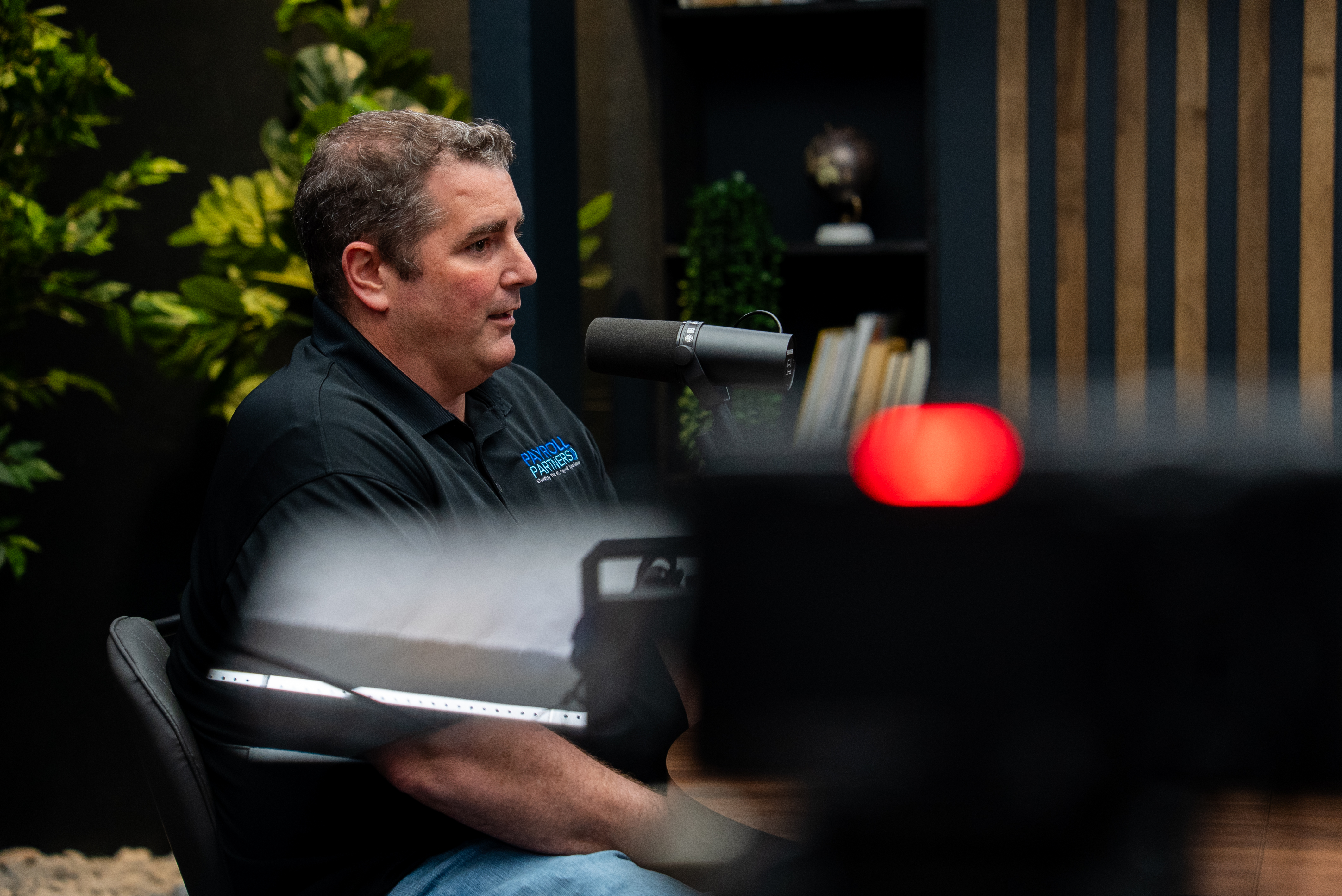 Presenter referencing notes during a course recording session in a professional studio