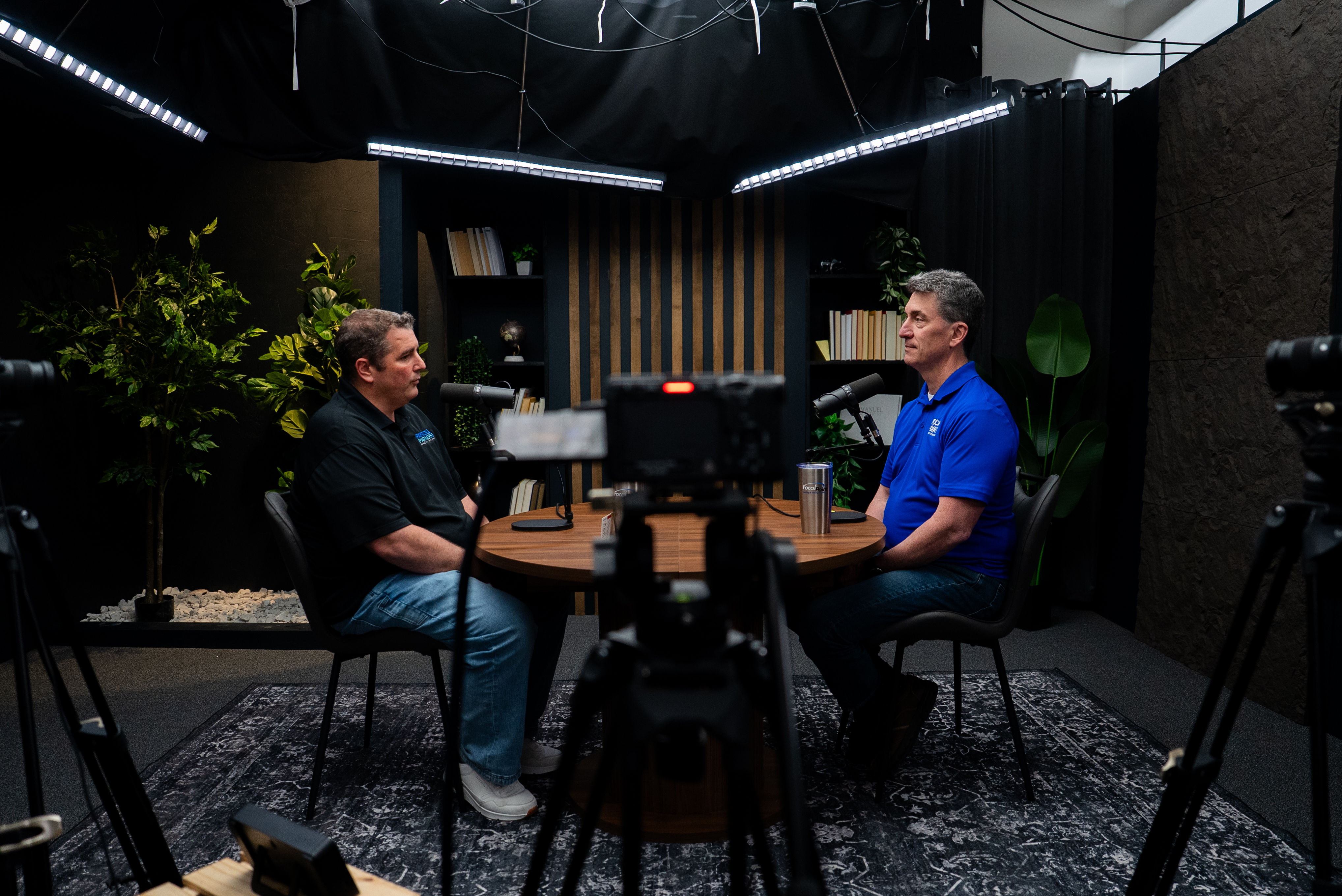 Podcast hosts recording an interview at a round studio table inside Cincinnati Podcast Studio