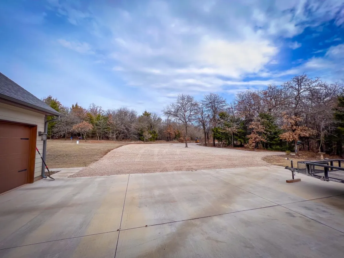 Gravel driveway and cleared pad next to a modern garage in rural Oklahoma – residential land grading and prep work