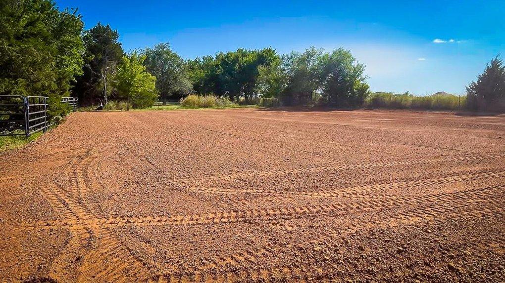 Freshly leveled pasture with red dirt and tire tracks in Oklahoma – land grading and surface prep services