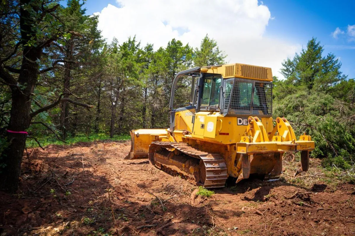 Yellow bulldozer clearing wooded area in rural Oklahoma – land clearing and site preparation service