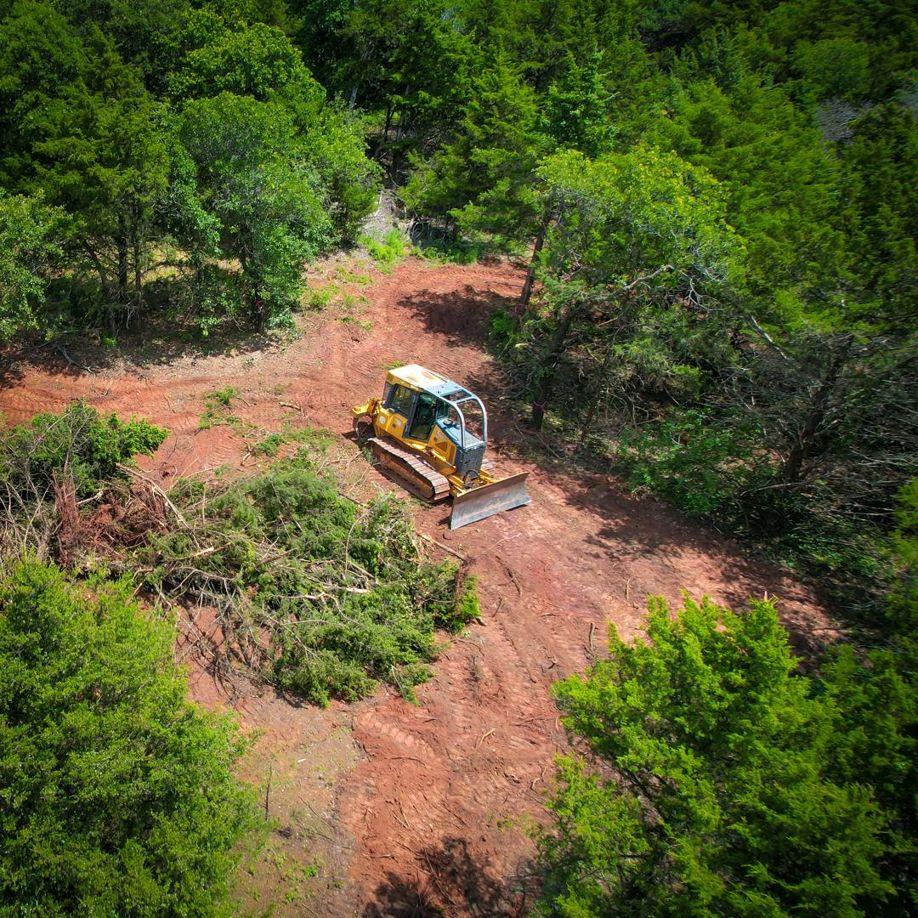 Aerial shot of bulldozer pushing brush piles during land grading in Oklahoma – excavation and clearing services