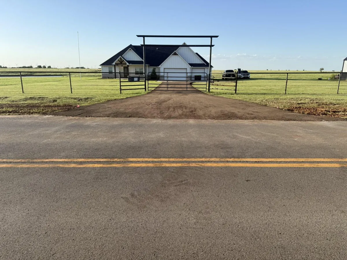 Gravel driveway leading to a rural property in Oklahoma, showcasing land clearing and site preparation work during spring.