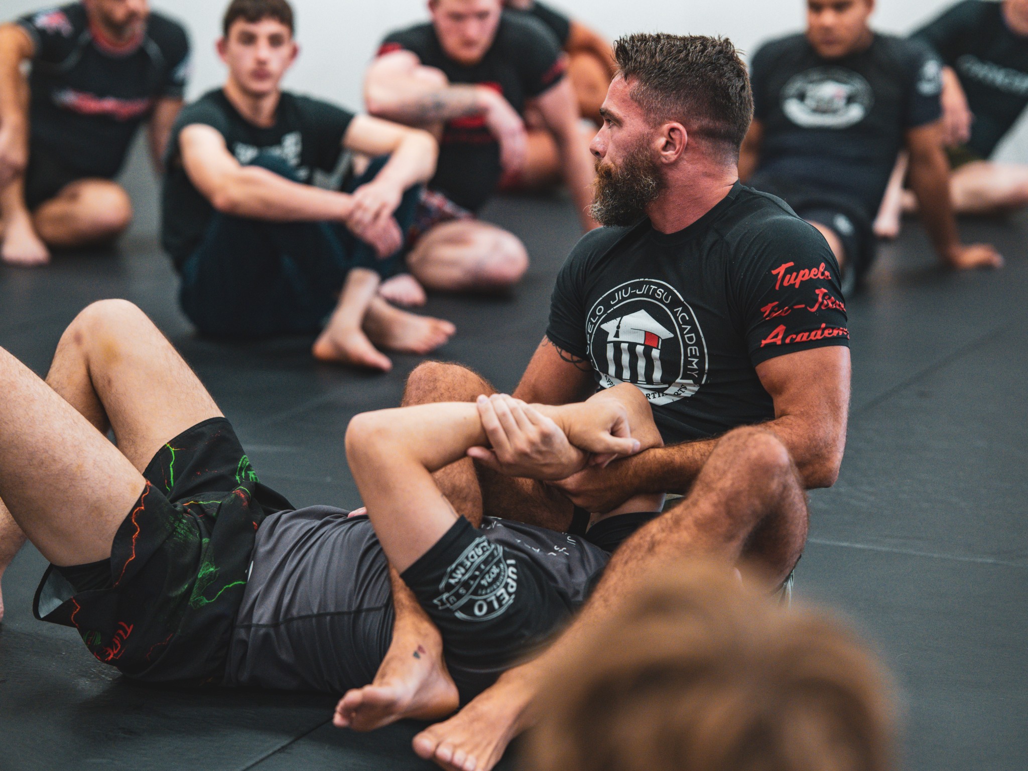 1. Brazilian Jiu Jitsu instructor demonstrating a grappling technique during class in Tupelo