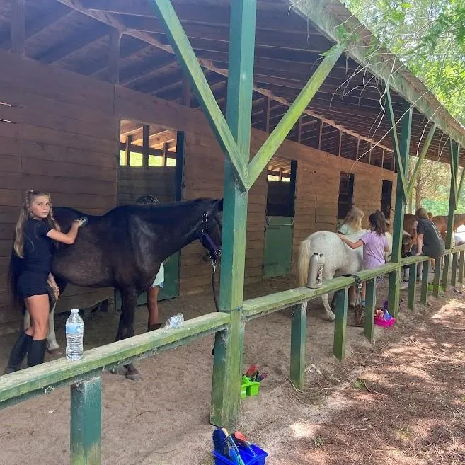 Trainer teaching girl how to tack